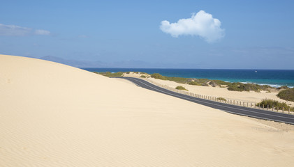 Sand dunes in Corralejo National Park and view of sea and road, Fuerteventura