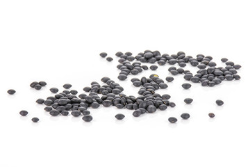 Lot of whole black lentils beluga variety isolated on white background