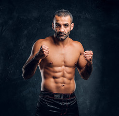 Portrait of a brutal professional fighter with naked torso posing for a camera. Studio photo...