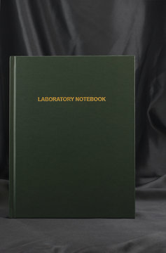 Laboratory notebook against elegant black satin background