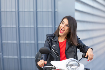 Fototapeta na wymiar Beautiful young girl in town with white motorbike and black leather jacket