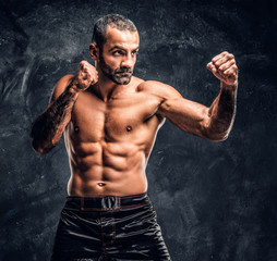 Obraz premium Professional fighter showing kick fighting technique. Studio photo against a dark textured wall