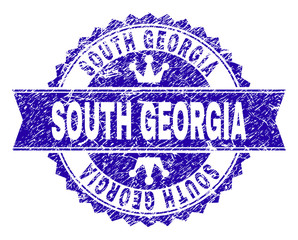 SOUTH GEORGIA rosette seal watermark with distress style. Designed with round rosette, ribbon and small crowns. Blue vector rubber watermark of SOUTH GEORGIA caption with grunge style.