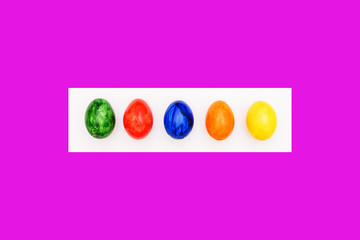 Multi-colored eggs on a purple and white background. Painted eggs. Handwork. Modern Art