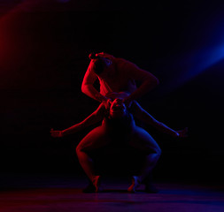 Young attractive couple dancing on the dance floor in a night club. Dancers performing in the dark...