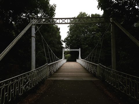 white and brown wooden bridge between trees during daytime