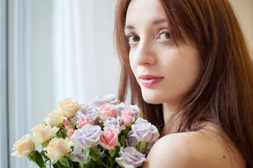 Attractive young brunette woman looking at the camera holding a bouquet of the flowers