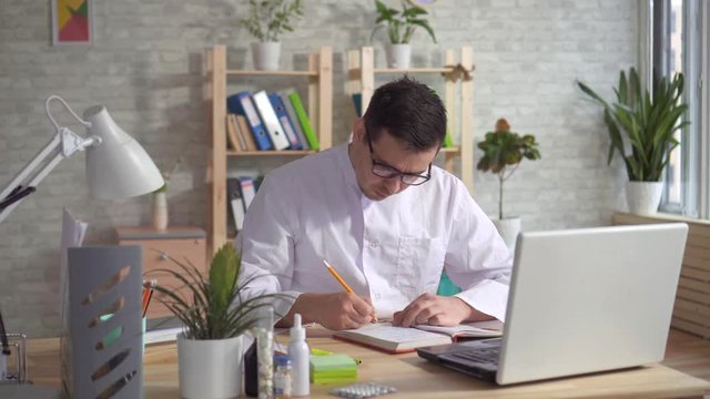 Man doctor working on laptop at office desk