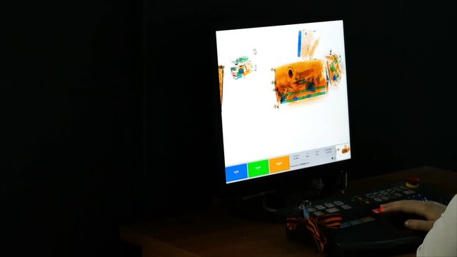 Checking airport security at the gate using an x-ray scanner, showing the contents of baggage on the monitor