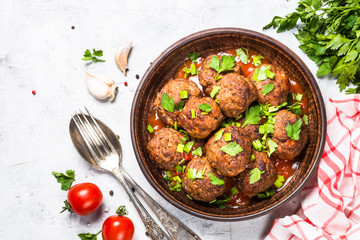 Meatballs in tomato sauce on light stone table top view. 