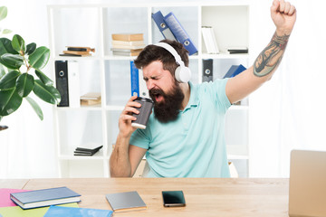 Regular office day. Man bearded guy headphones sit office listen music sing song. Worker with...