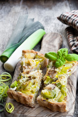 Leek tart with bacon and cheese on wooden table