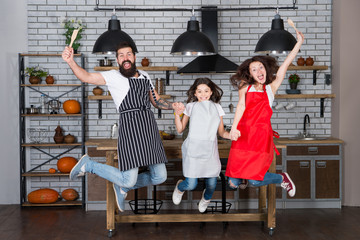 Family cuisine. Home interior. Culinary school. Happy family in kitchen. Mother and father with little girl. Little girl with parents in apron. Father, mother and child chef cooking. Family day.