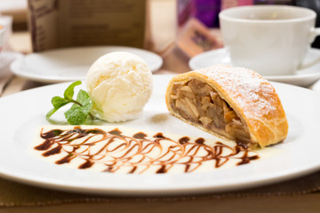 strudel on a white plate with a scoop of ice cream and mint leaves