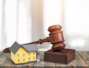 Wooden judge gavel and toy  house on  background