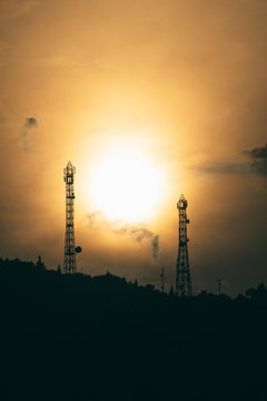silhouette photograph of two communication towers during golden hour