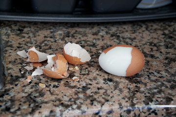 Hard boiled eggs with shell beside on granite board (Selective Focus, Focus on the front of the shell on the first egg).