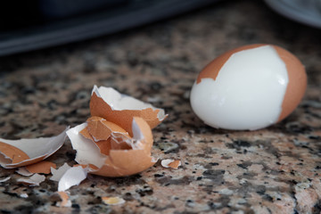 Hard boiled eggs with shell beside on granite board (Selective Focus, Focus on the front of the shell on the first egg).