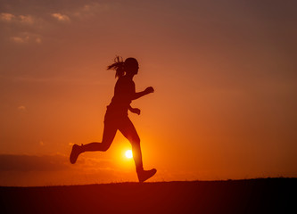 Obraz na płótnie Canvas Silhouette of the running girl at sunrise.