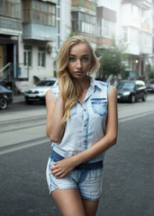 Beautiful blonde sexy tourist girl walking on a busy city street with long hair. A woman in a denim jacket looks into the camera. Lifestyle in New York
