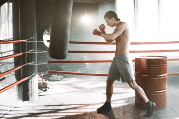 punching boxer on boxing ring, black bacground, horizontal photo