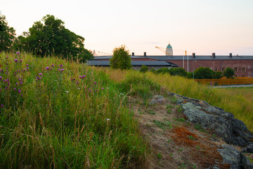 Fototapeta na wymiar View of the old historic barracks in the fortress on the island-fort Suomenlinna Sveaborg in Finland in the summer evening, stones, grass and traditional Finnish landscape.