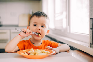 beautiful baby in orange t-shirt with orange plate eating fried French fries