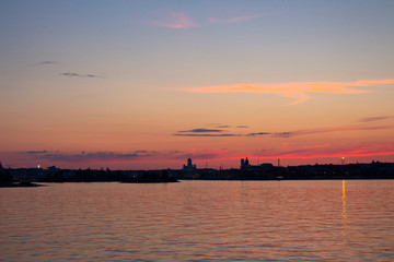 View of the silhouettes of the city of Helsinki from the Gulf of Finland at dusk on a bright summer night in the capital of Finland. Background with place for text.