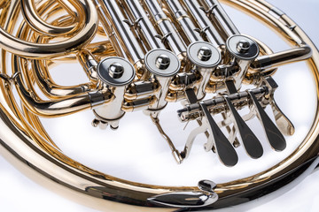 French horn on a white table. Beautiful polished musical instrument.