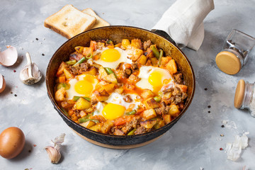 Homemade Hearty Breakfast Skillet with Eggs Potatoes and minced meat on concrete table