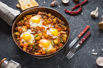 Homemade Hearty Breakfast Skillet with Eggs Potatoes and minced meat on stone table