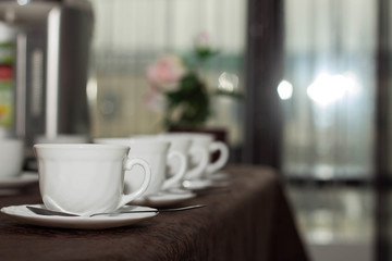 white cups of tea are in a row on the table with a brown tablecloth
