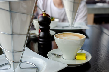 A cup of coffee on the table in the restaurant. Chocolate on the saucer with coffee