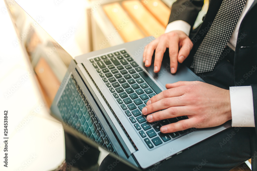 Wall mural cropped image view of man's hands in elegant suit keyboarding on laptop computer with blank copy spa