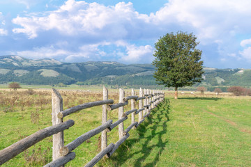 Wooden fence in the field on the background of mountains. Beautiful village landscape. Stock image.