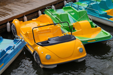 Parking of colorful water bicycles on a river after rain.