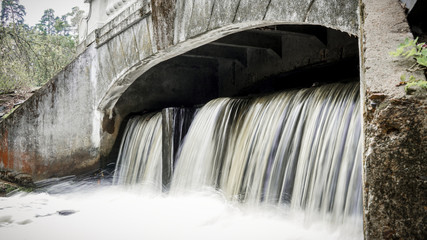 small waterfall flowing from a samll dam in the park