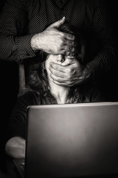 Woman Typing On A Computer With A Hand Covering Her Eyes And Mouth