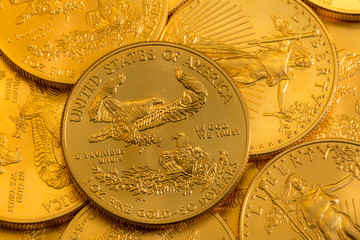 Pile of golden coins with Gold Eagle on US Treasury issue one ounce pure gold coin