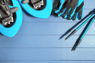 Flat top view on winter hiking equipment and gear such as snowshoes, trekking poles and blue gloves with copy space for sports and recreation text