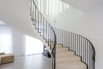 spiral staircase in bright interior with white brick wall in elite expensive apartment
