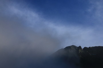 Naklejka na ściany i meble 北アルプス　神々しい上高地の朝の風景　雲に煙る穂高連峰と明神岳