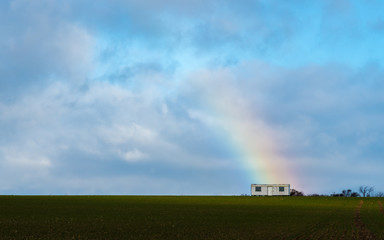 Fototapeta na wymiar The trailer with a rainbow on a field