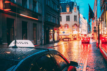 Taxi Car Wait Clients In Old European Streets  In Rainy Evening. Night Street Illuminations