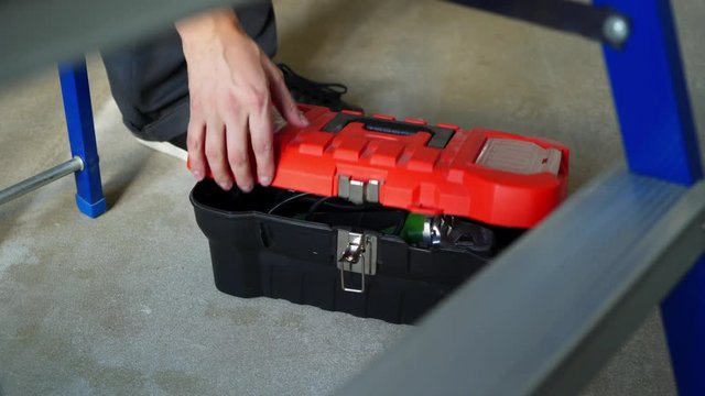 Man worker opens toolbox and takes circular saw tool