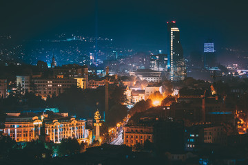 Tbilisi, Georgia. Construction Development Of Modern Architecture On Background Of Urban Night Cityscape. Evening Night Scenic Aerial View Of City Center