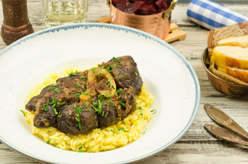 Beef osso bucco with risotto on rustic background. 