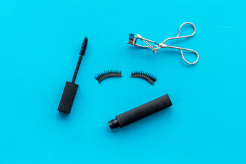 decorative cosmetic set with lash curler and mascara on blue woman desk background top view