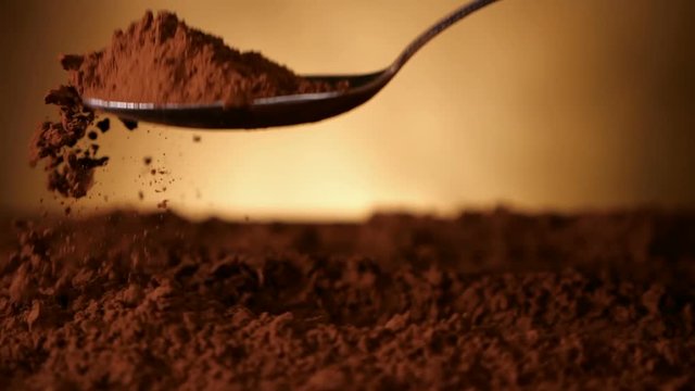 Hand with spoon pushing through cocoa powder lifting up a spoonful - close up, slow motion, camera follow motion