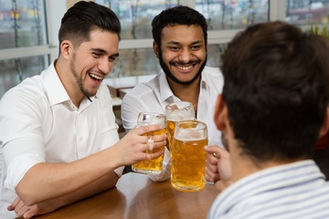 The week is over. Shot of happy laughing businessmen enjoying drinks at the local pub after a workday
